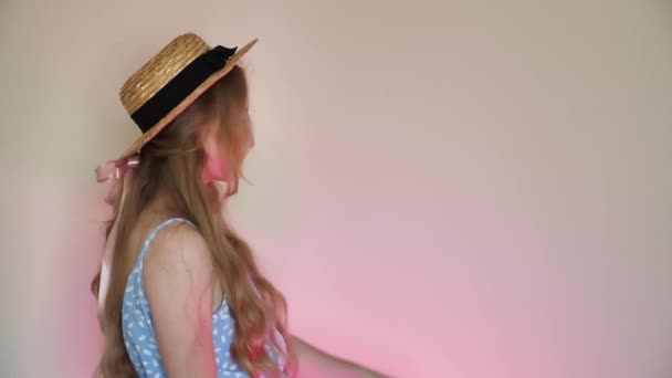Žena blondýna s růžovou stuhou, slaměný klobouk v dlouhých vlasech v modrých šatech nosí tašku. Detailní záběr, izolovaný, vložit text, kopírovací prostor, kopírovat vložení - Záběry, video