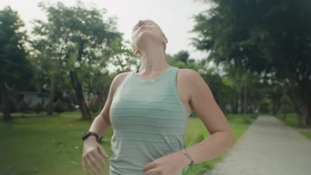 Arc tour de taille plan de la femme sportive faisant de l'exercice d'étirement tout en se réchauffant avant l'entraînement en plein air dans le parc - Séquence, vidéo