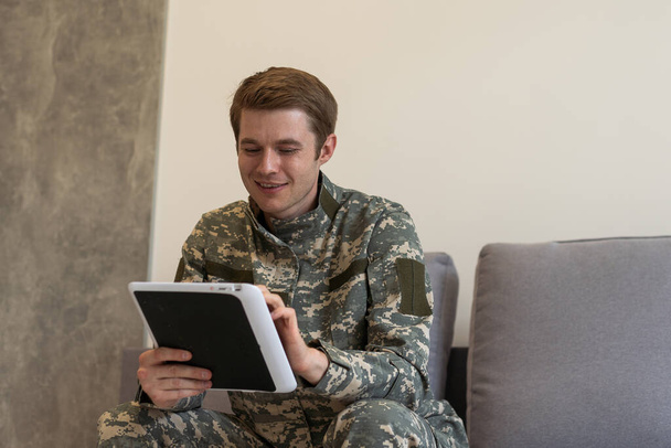Um militar a acenar. homem militar acenando enquanto tem vídeo chat com a família no tablet. - Foto, Imagem