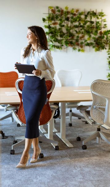 Giovane donna d'affari con tablet digitale in piedi nel moderno ufficio - Foto, immagini