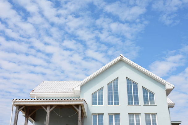 Vista exterior de um design de janela triangular, janelas de forma irregular do espaço de segundo nível, varanda, sótão ou sótão de uma casa moderna azul clara com um telhado branco. - Foto, Imagem