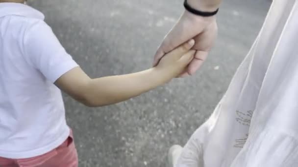 Близко и лично - мать и ребенок держатся за руки, когда идут по тротуару - Кадры, видео
