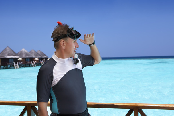 O homem de esportes em um terno de um snorkeling no convés solar de uma casa sobre o mar. Maldivas
 - Foto, Imagem