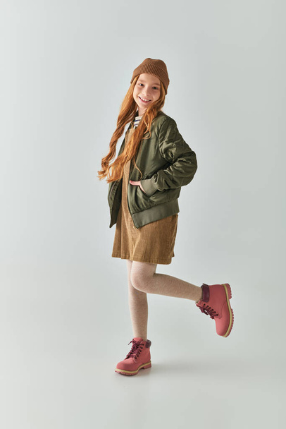 child fashion, happy girl with long hair and winter hat on head standing in dress and jacket - Foto, Imagem