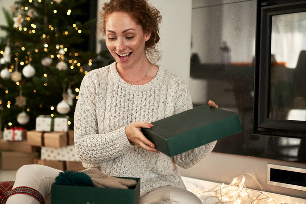 Fröhliche Frau packt Geschenke für Weihnachten aus - Foto, Bild