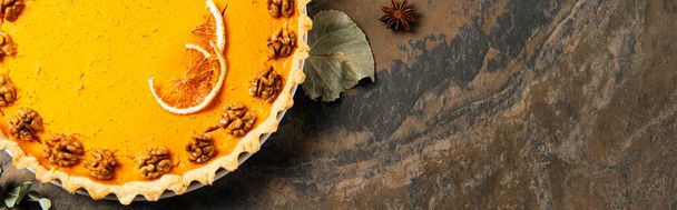 Thanksgiving traktatie, zelfgemaakte pompoentaart met walnoten en sinaasappelschijfjes op stenen achtergrond, banner - Foto, afbeelding