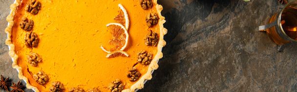 herkullinen kiitospäivän symboli, kurpitsapiirakka saksanpähkinöillä ja appelsiiniviipaleilla kivipohjalla, banneri - Valokuva, kuva