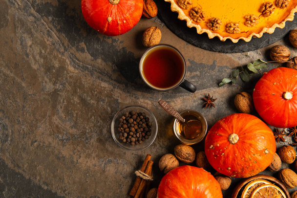 Erntedank-Thema, hausgemachter Kürbiskuchen in der Nähe von Kürbissen, warmer Tee und aromatischer Honig auf Steintisch - Foto, Bild