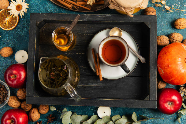 configuração de ação de graças colorida, bandeja de madeira preta com chá de ervas e mel perto de objetos de colheita de outono - Foto, Imagem