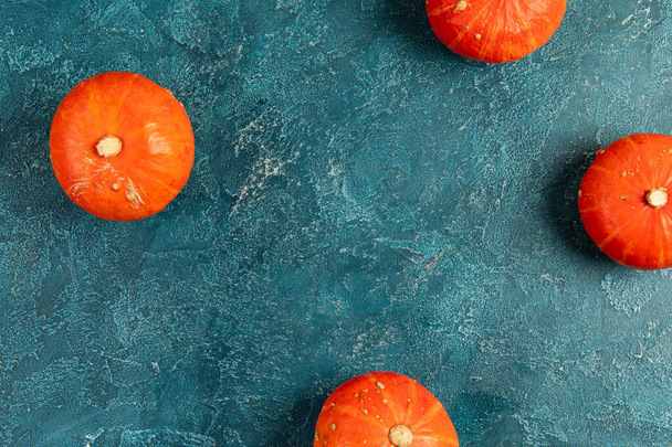 sfondo del Ringraziamento, zucche arancione brillante su blu strutturato tavolo, prospettiva dall'alto verso il basso - Foto, immagini