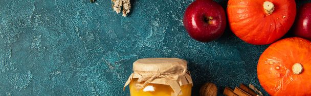 гарбузи та червоне яблуко біля баночки меду на синій текстурованій поверхні, життя подяки, банер - Фото, зображення