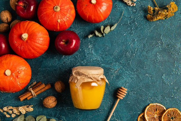 dankzegging thema, pompoenen in de buurt van pot honing en herfst oogsten objecten op blauwe textuur oppervlak - Foto, afbeelding