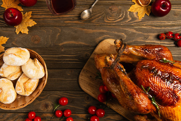 thanksgiving turkey and buns on wooden table with golden foliage and red cherry tomatoes with apples - Photo, Image