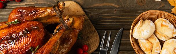 delicious thanksgiving turkey and freshly baked bread near cutlery on textured wooden table, banner - Photo, Image