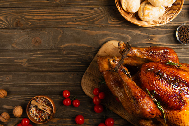 Thanksgiving diner, vers gebakken brood en rode kerstomaten bij geroosterde kalkoen op houten tafel - Foto, afbeelding