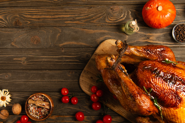 grilled turkey and freshly baked buns near spices and cherry tomatoes on wooden table, thanksgiving - Foto, Imagem