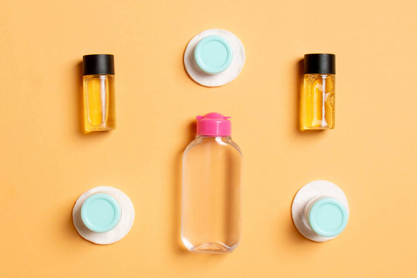 Top view of means for face care: bottles and jars of tonic, micellar cleansing water, cream, cotton pads on colored background. Bodycare concept with empty cpace for your ideas. - Photo, Image