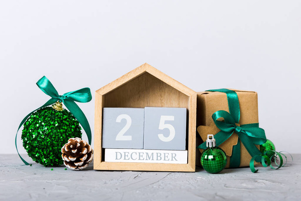 25 december. Christmas composition on colored background with a wooden calendar, with a gift box, toys, bauble copy space. - Photo, image