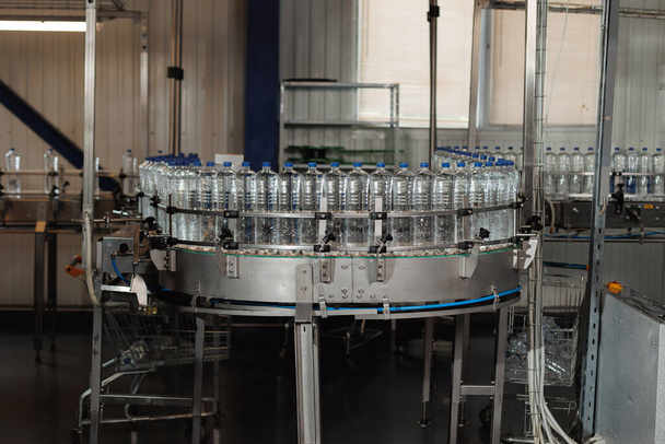 Des machines de pointe assurent un remplissage rapide des bouteilles en plastique vides avec de l'eau. - Photo, image