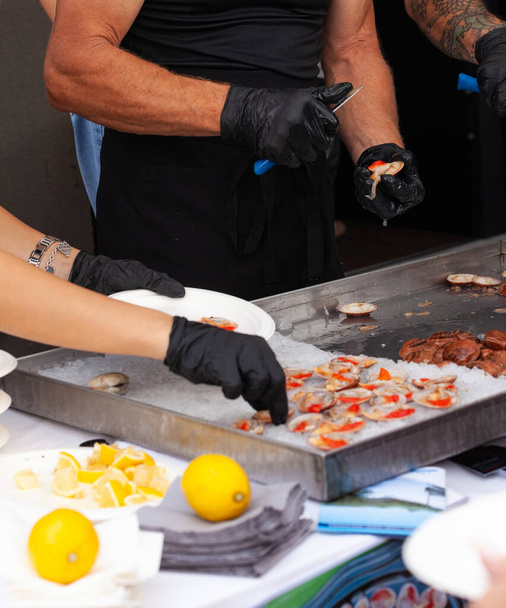 Ресторан готує смачні страви з сирих гладких молюсків, поки рибалка відкриває гладку молюск - Фото, зображення