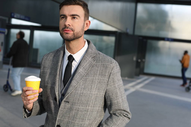 ritratto di bel giovane in abito grigio con tazza di carta di caffè sulla strada della città - Foto, immagini
