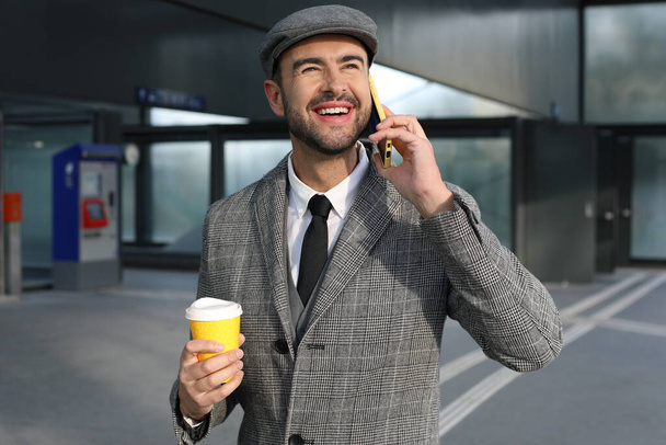 Porträt eines hübschen jungen Mannes im grauen Anzug mit Pappbecher Kaffee auf der Straße der Stadt - Foto, Bild