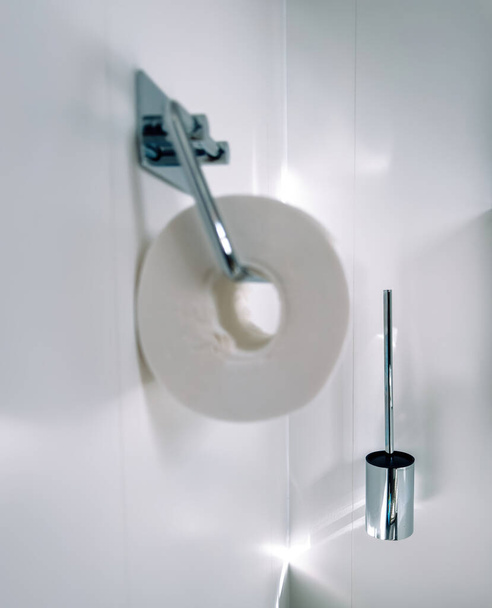 W nowoczesnej łazience skupiamy się na chromowanej szczotce do toalety obok uchwytu na papier toaletowy. - Zdjęcie, obraz