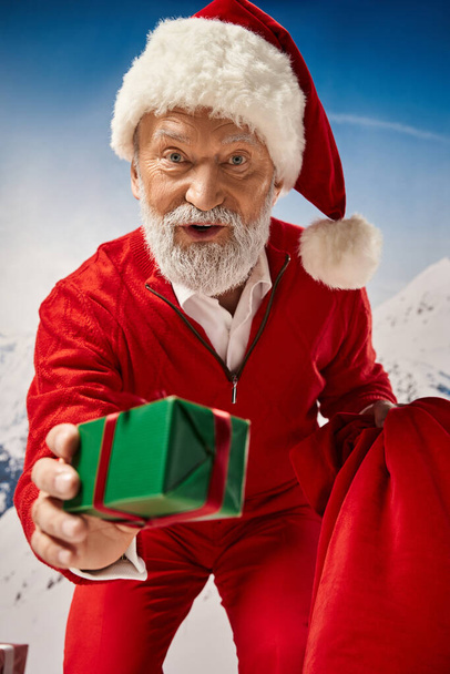 blanc barbu Père Noël prêt cadeau avec ruban rouge et regarder la caméra, concept d'hiver - Photo, image