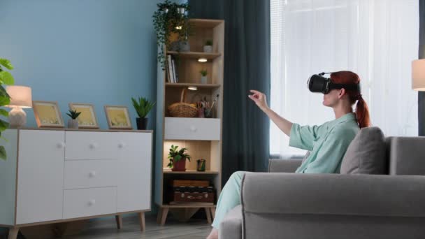 tecnologia moderna, donna seduta in occhiali realtà virtuale guarda pagina Internet e sito web mentre seduto sul divano in camera - Filmati, video