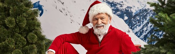 hombre alegre vestido como Papá Noel en sombrero navideño con fondo nevado, concepto de invierno, bandera - Foto, Imagen