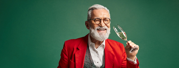 jolly Santa in red elegant suit testing champagne and smiling at camera, winter concept, banner - Photo, Image