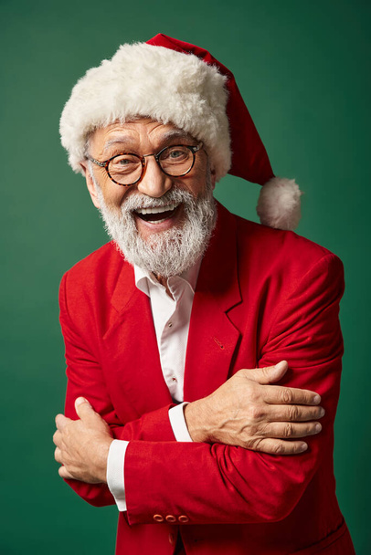 homme gai habillé en Père Noël posant sur fond vert et souriant à la caméra, concept d'hiver - Photo, image