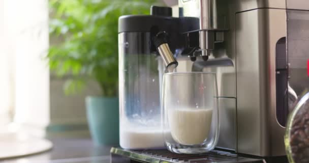 Koffiemachine bereiden en verdelen schuimmelk in glazen beker om cappuccino of latte te maken. Hoge kwaliteit 4k beeldmateriaal - Video