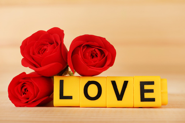 Decorative letters forming word LOVE with flowers on wooden background - Foto, Imagen