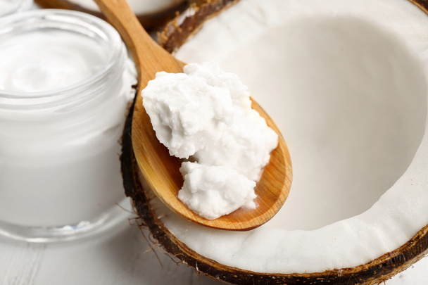 Coconut with coconut oil and jar of cosmetic cream on table close up - Valokuva, kuva