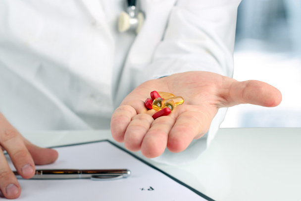 Médecin dans un manteau blanc donnant des pilules
 - Photo, image