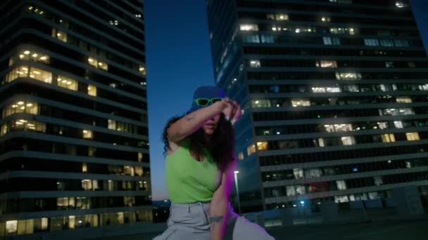 Krásná smíšená závodnice na diskotéce na střeše. Portrét okouzlující ženy tančící na neonových světlech ve městě zpomaluje. Sexy cool dívka zírá na kameru v noci v centru pozadí - Záběry, video