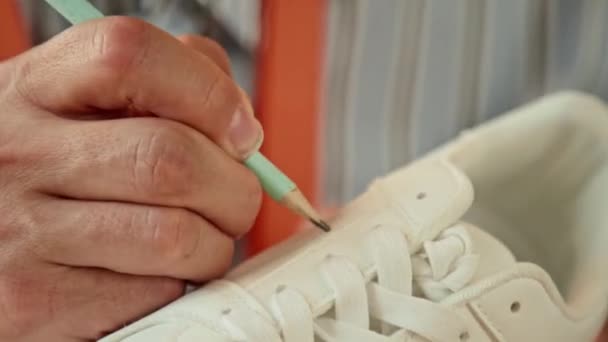 Nahaufnahme von männlichen kreativen Designern, die Skizzenlinien auf weißen Turnschuhen zeichnen - Filmmaterial, Video