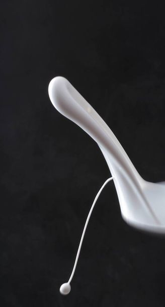 a vertical closeup shot of a white and white spoon isolated on a black background - Photo, Image