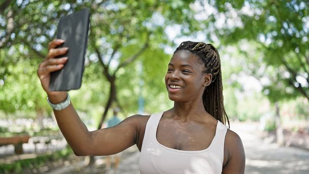 Африканська американська жінка посміхається впевнено робить селфі на тачпад в парку - Фото, зображення