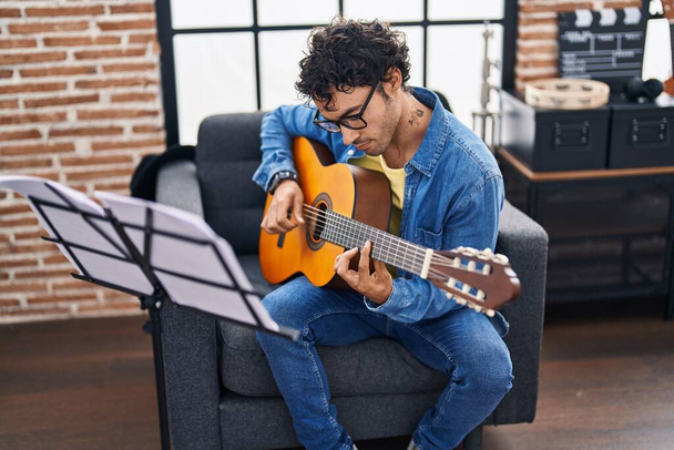 Joven músico hispano tocando la guitarra clásica en el estudio de música - Foto, imagen