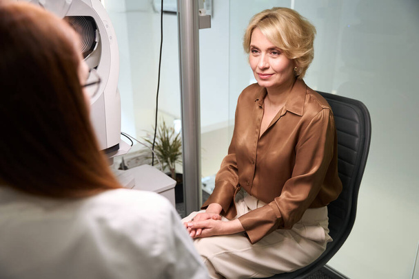 Piacevole donna di mezza età ad un appuntamento con un oftalmologo, la clinica ha attrezzature moderne. - Foto, immagini