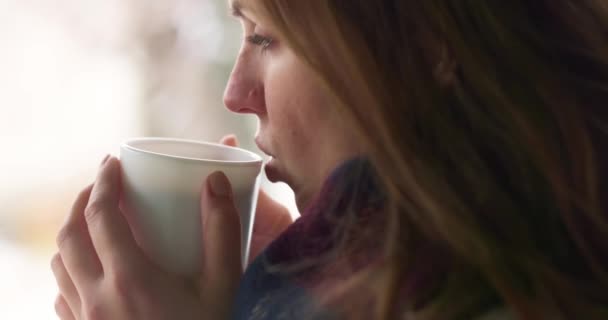 Симпатичная женщина с белой чашкой пьет горячий шоколад, чай или кофе в снежную зимнюю погоду на открытом воздухе. Высококачественные 4k кадры - Кадры, видео