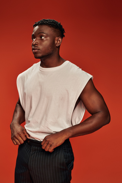 hot african american guy in white tank top standing and looking away on red, urban fashion - Φωτογραφία, εικόνα