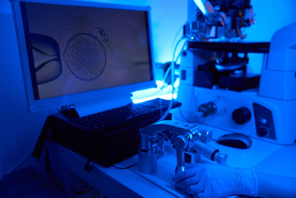 Обрізана фотографія репродуктивного вченого, який працює з обладнанням для мікроманіпуляції під час процедури ICSI - Фото, зображення