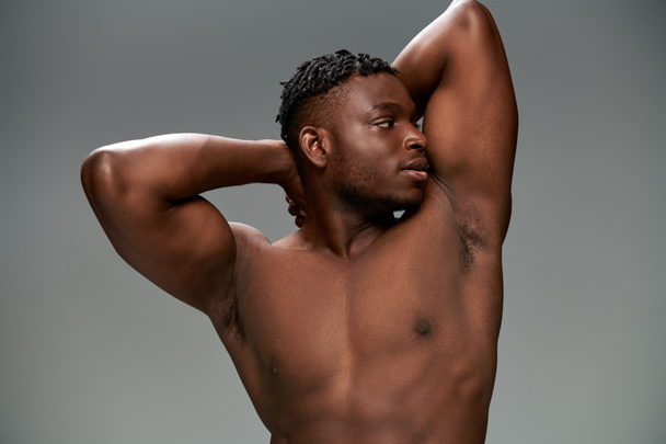 sportive and shirtless african american man with muscular body posing with hands behind head on grey - Photo, Image