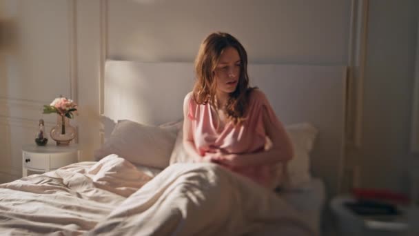 A nő hasfájást érez az ágyban. Frusztrált ébren lévő lány megérinti hasi szenved gyomorhurut hasmenés fájdalmas időszak otthon. Az aggódó nősténynek menstruációs görcse van. Élelmiszer-mérgezés fogalma - Felvétel, videó
