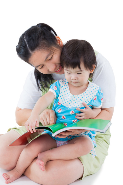 Young female with little asian girl reading a book - Фото, зображення