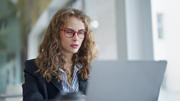 近代的なオフィスに座っているメガネを持つ若い実業家 - 映像、動画