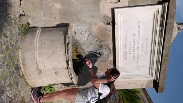 Ostia Antica Itálie, 29. května 2023: Vertikální video dívky popíjející z fontány v obci - Záběry, video